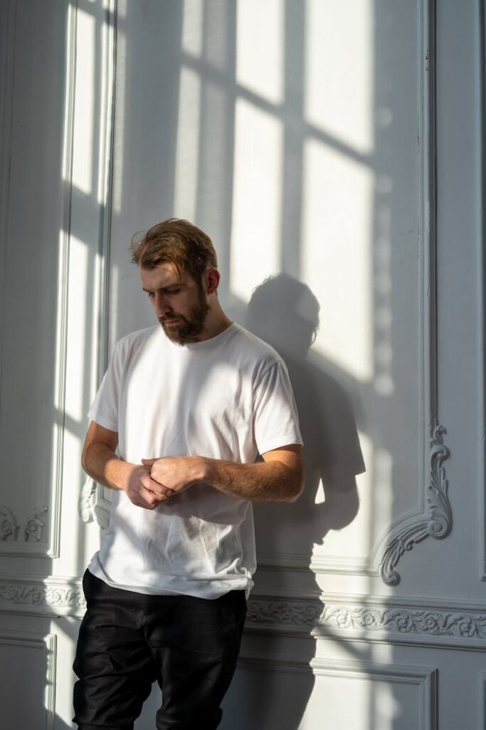 zipwp-image-4101142 Man in White Crew Neck T-shirt Standing Beside Window
